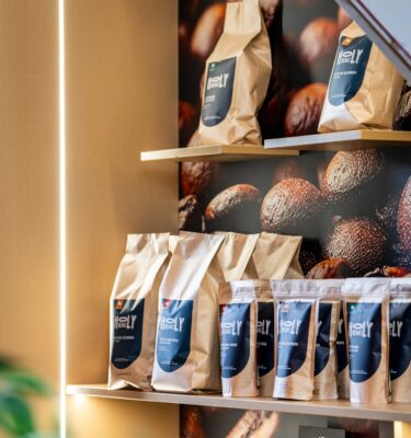 Het schap met zakken Holy Beans koffie van 200 gram en 1 kilo in de winkel van De Hemel in Nijmegen