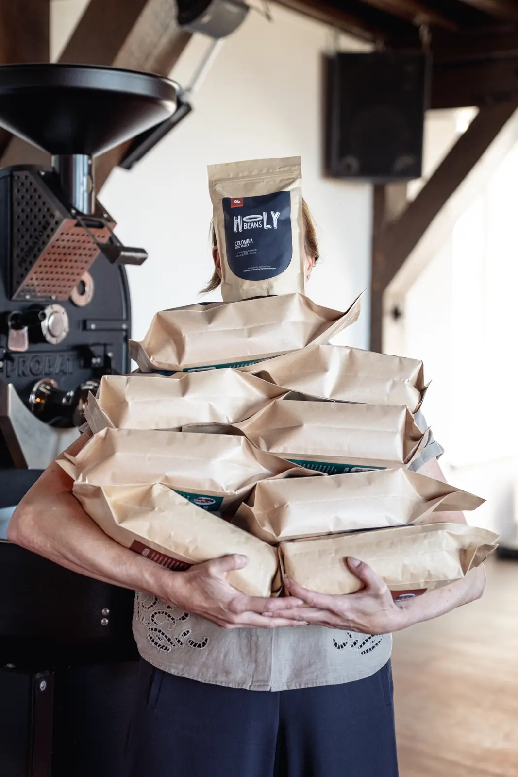 Ilfa de Roo met een arm vol gevulde zakken Holy Beans koffie voor de koffiebrander