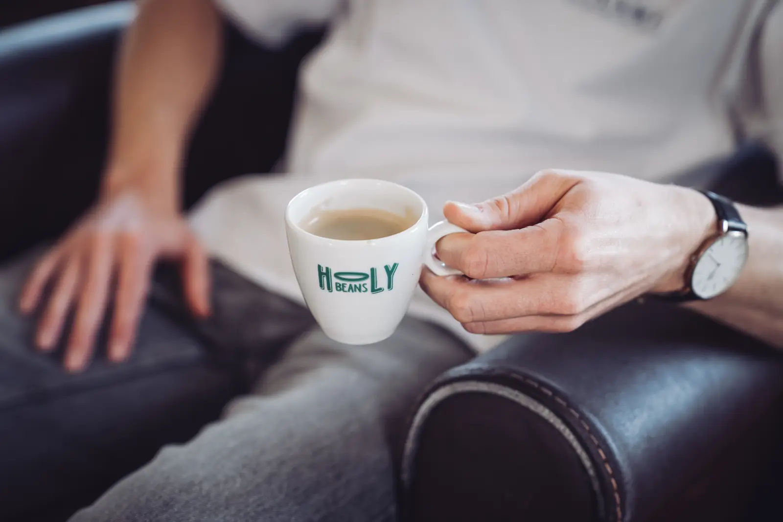 Een kop Holy Beans koffie in twee handen